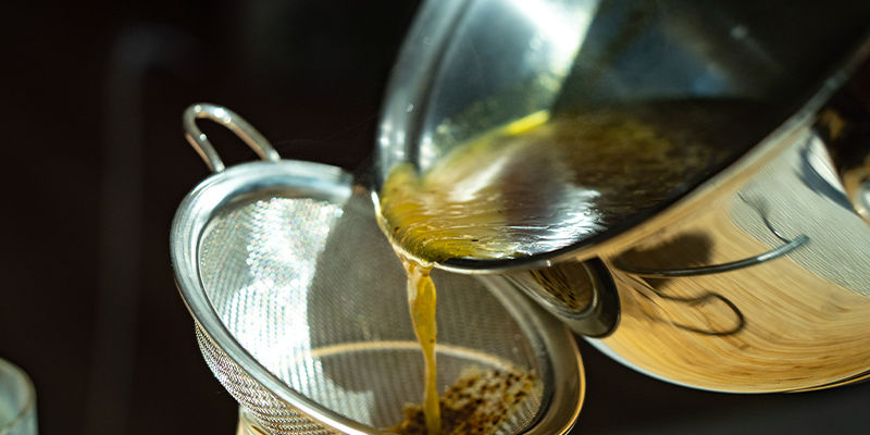 Seih Die Mischung In Einen Anderen Behälter Ab, Um Das Pflanzenmaterial Zu Entfernen Seih Die Mischung In Einen Anderen Behälter Ab, Um Das Pflanzenmaterial Zu Entfernen